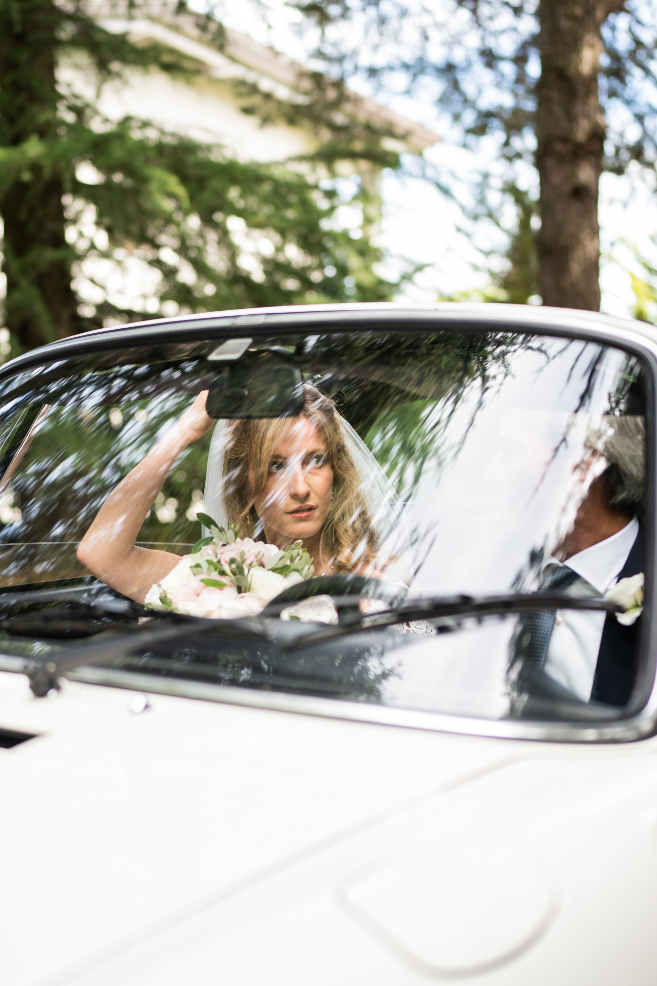 La sposa nell'auto, riflessi tra gli alberi